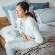 Woman with abdomen problems in bed, she use hands to massage painful place